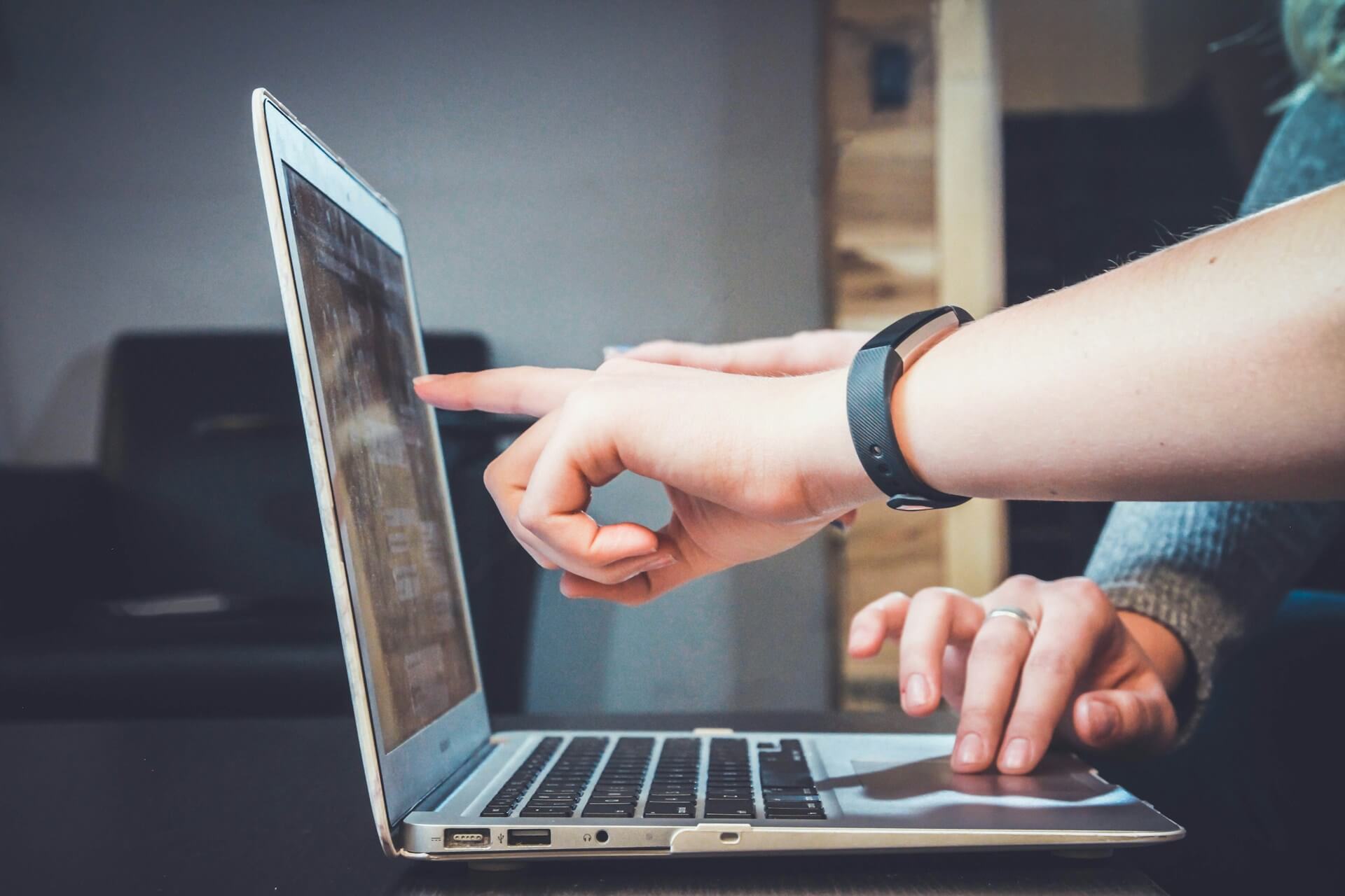 a person pointing at a laptop