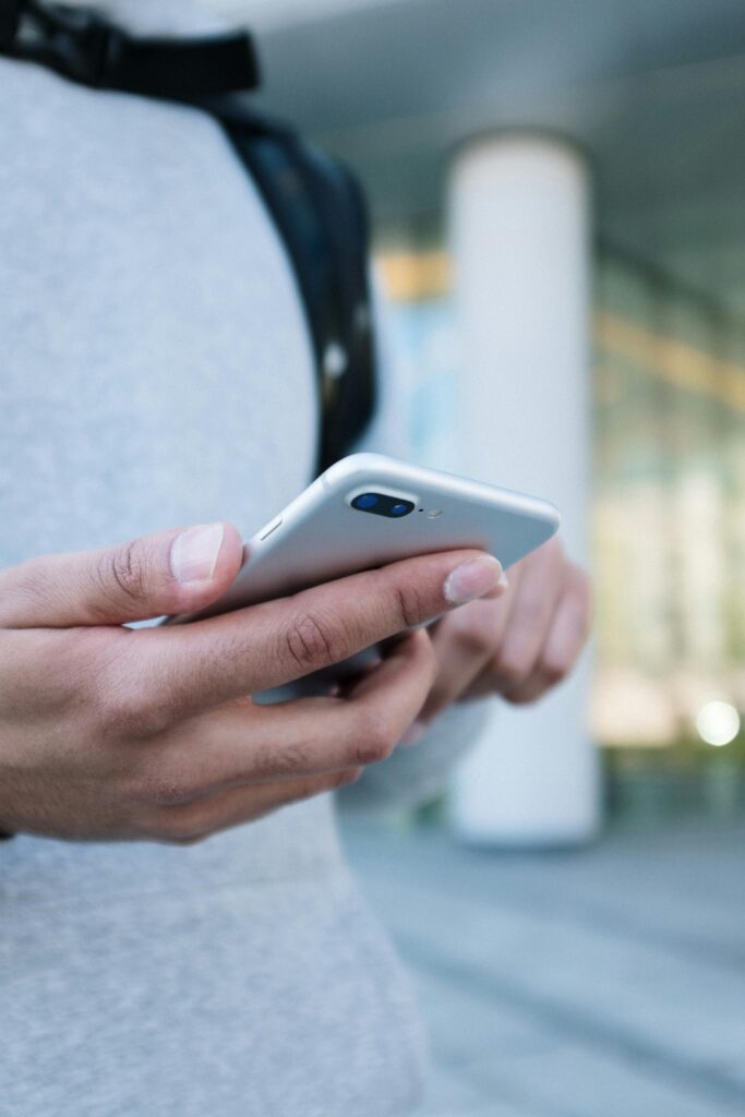 Close-up of hands holding a smartphone outdoors, focused on the device.